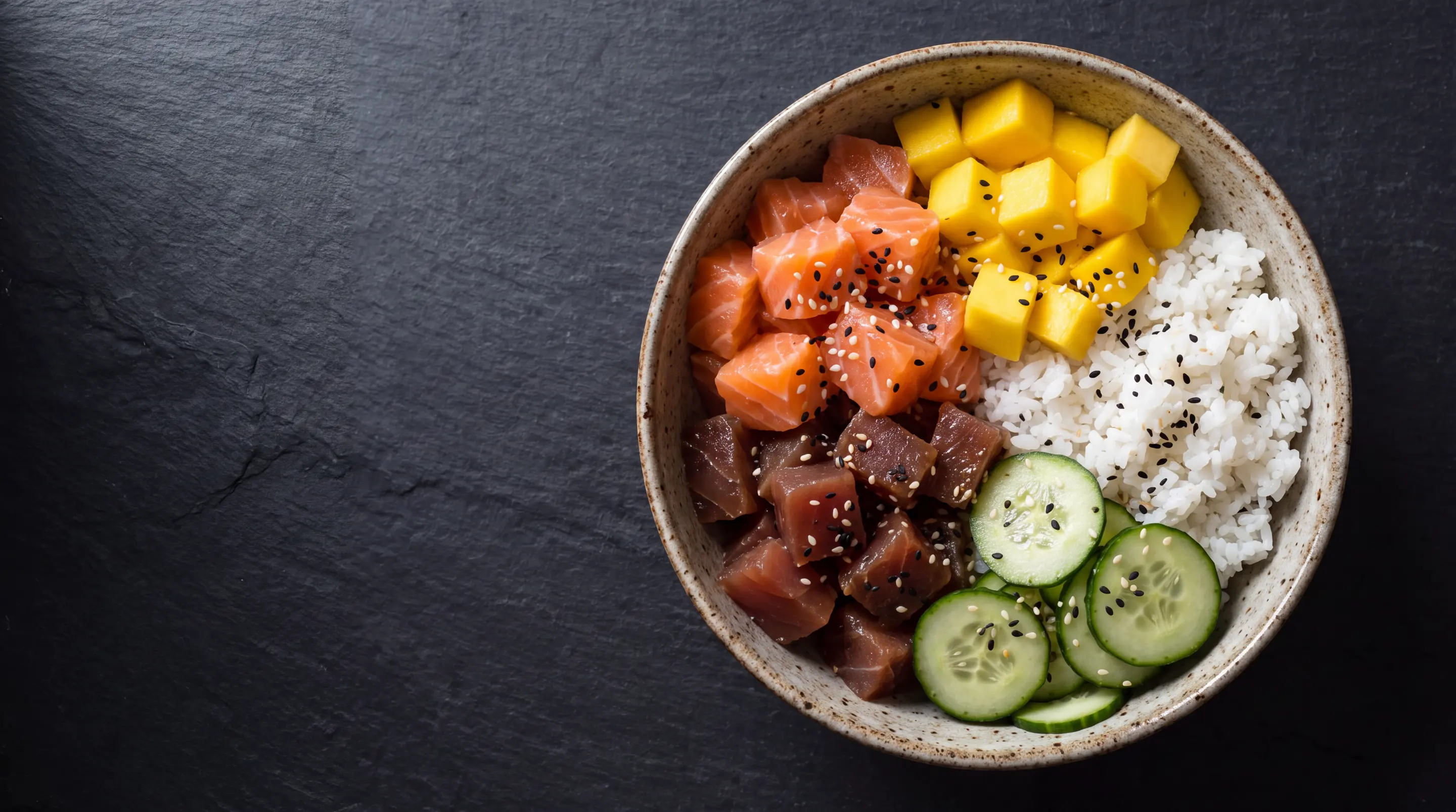Poke bowl con salmón, atún, arroz, mango y pepino visto desde arriba